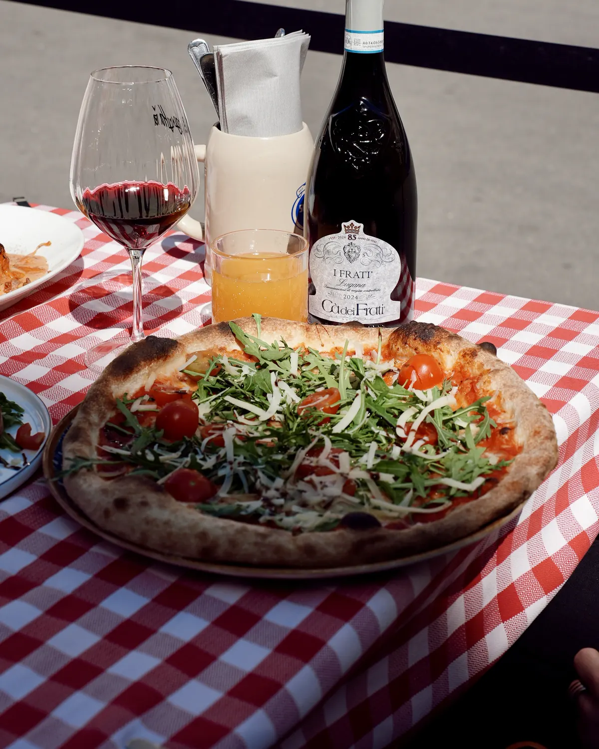 Pizza und Rotwein auf kariertem Tischtuch bei La Pizzetta
