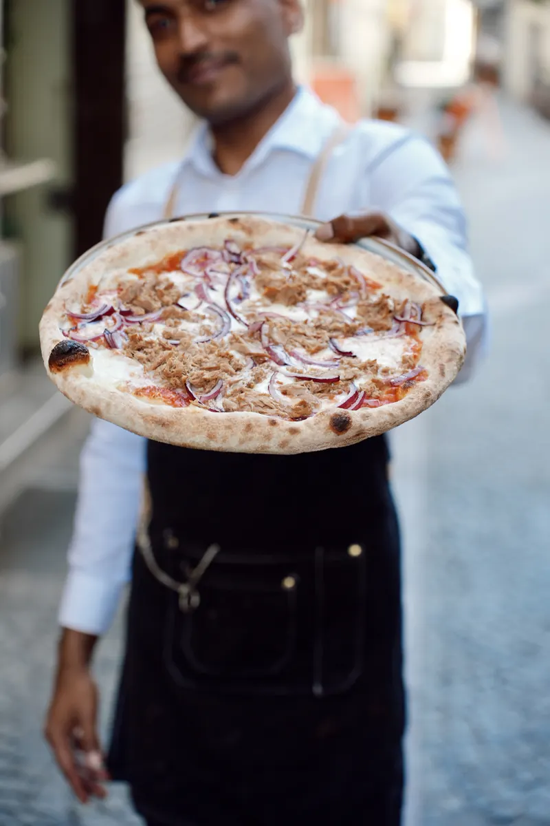 Kellner mit Pizza bei La Pizzetta